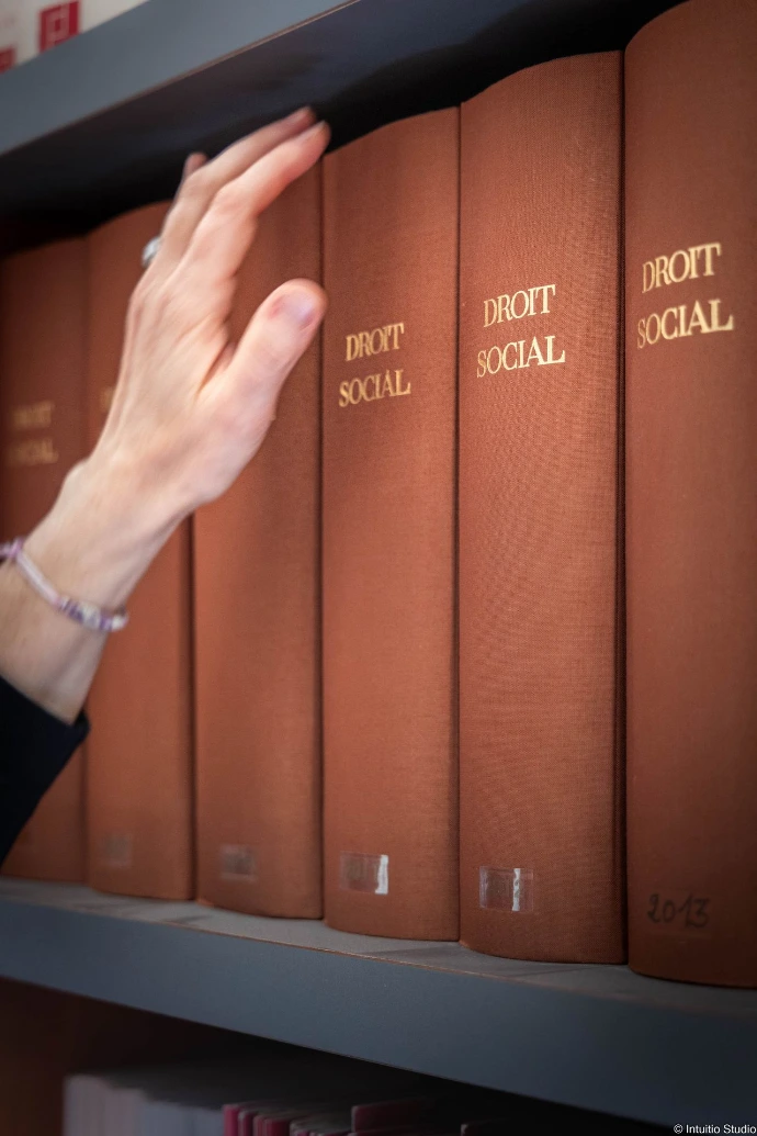 Une main devant une rangée de codes de droit social