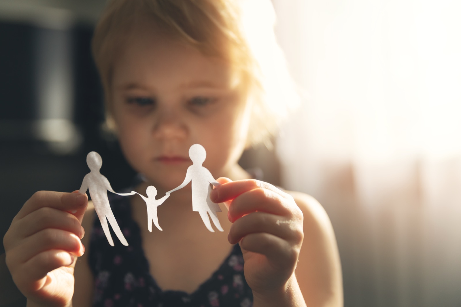 Un enfant tenant une famille en papier sur le point de se déchirer